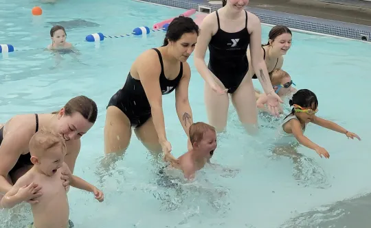 Adults in the shallow pool with children learning acclimate to the watter