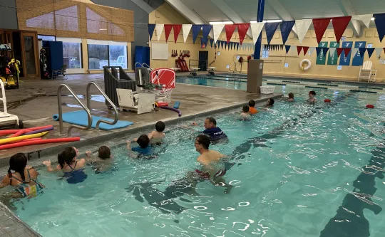 group of kids in the pool holding the edge