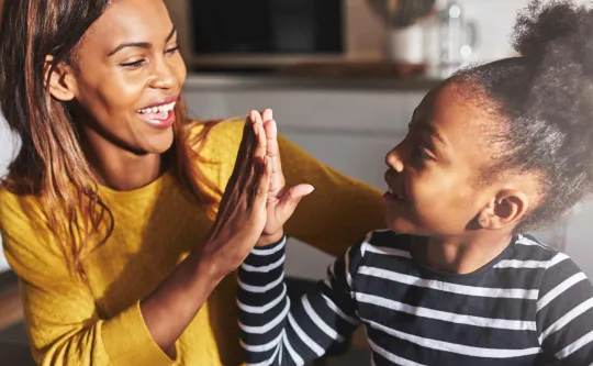 Black woman high fiving a black child