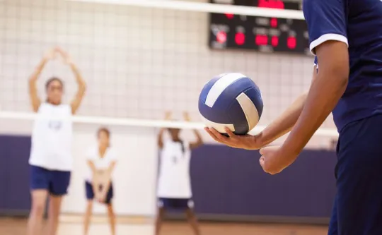 Boys playing volleyball in a gymnasium