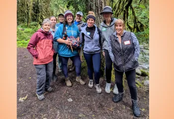 Group photo of people of varying ages and genders in hiking gear on a group hike