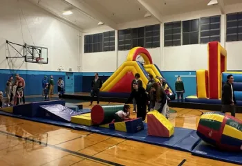 Gymnasium full of families playing on bouncy house and other play equipment