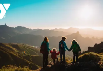 Photo of a woman and three children hiking in the mountains looking at a sunset