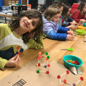 children sitting at a table making craft structures out of gumdrops and tootpicks