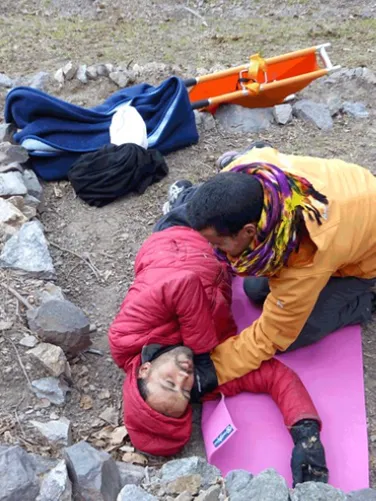 Person helping a prone injured person in the woods