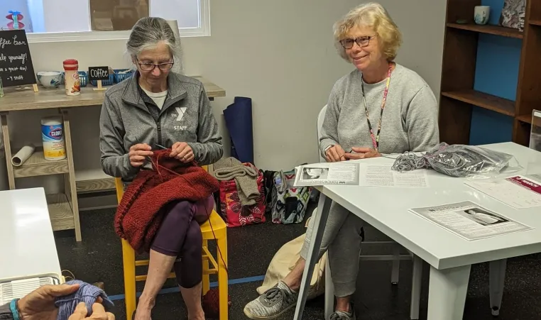 Two women sitting together knitting for adult enrichment