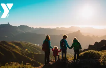 Photo of a woman and three children hiking in the mountains looking at a sunset