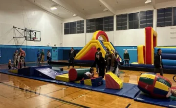 Gymnasium full of families playing on bouncy house and other play equipment