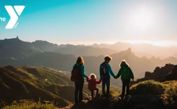 Photo of a woman and three children hiking in the mountains looking at a sunset